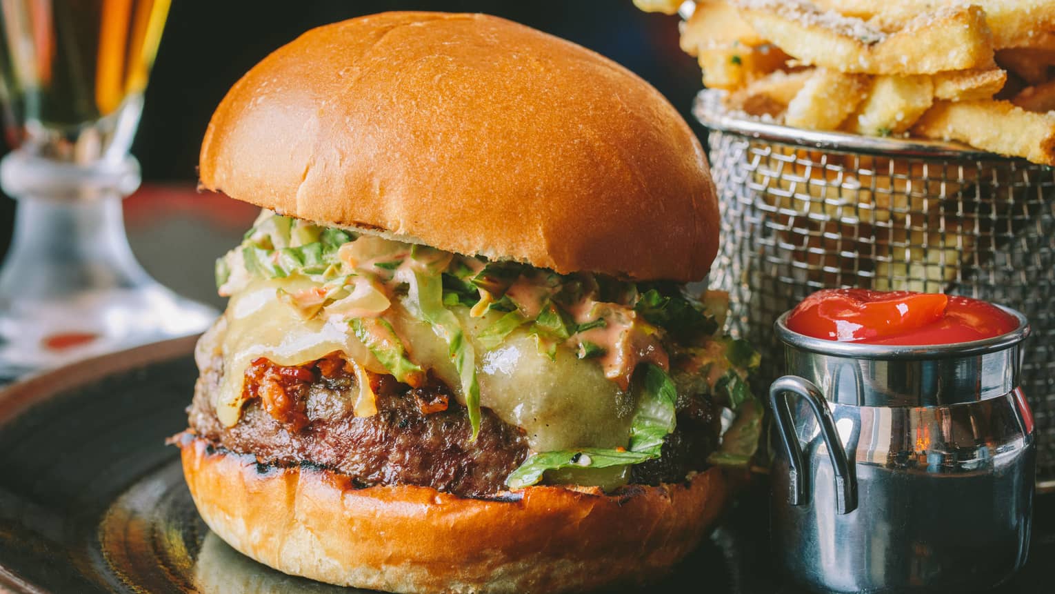 Cheeseburger, small tin of ketchup and a wired metal container of french fries
