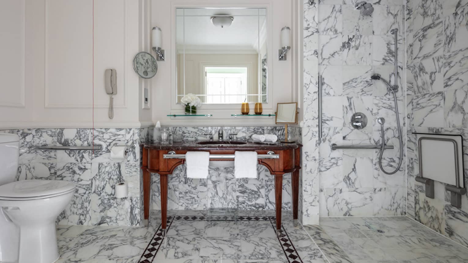 Bathroom with marble shower and glass door, porcelain commode, double wooden vanity, mirror