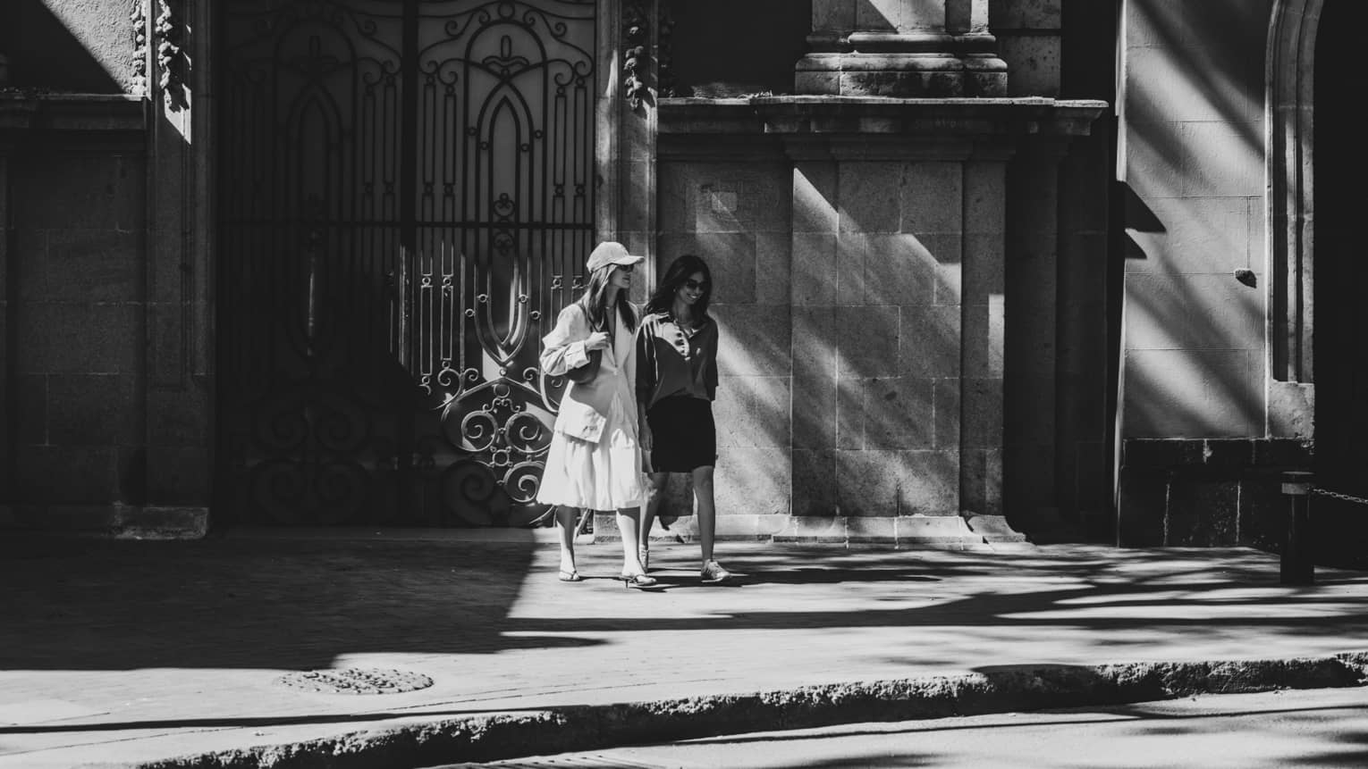 Two people stroll along a city sidewalk.