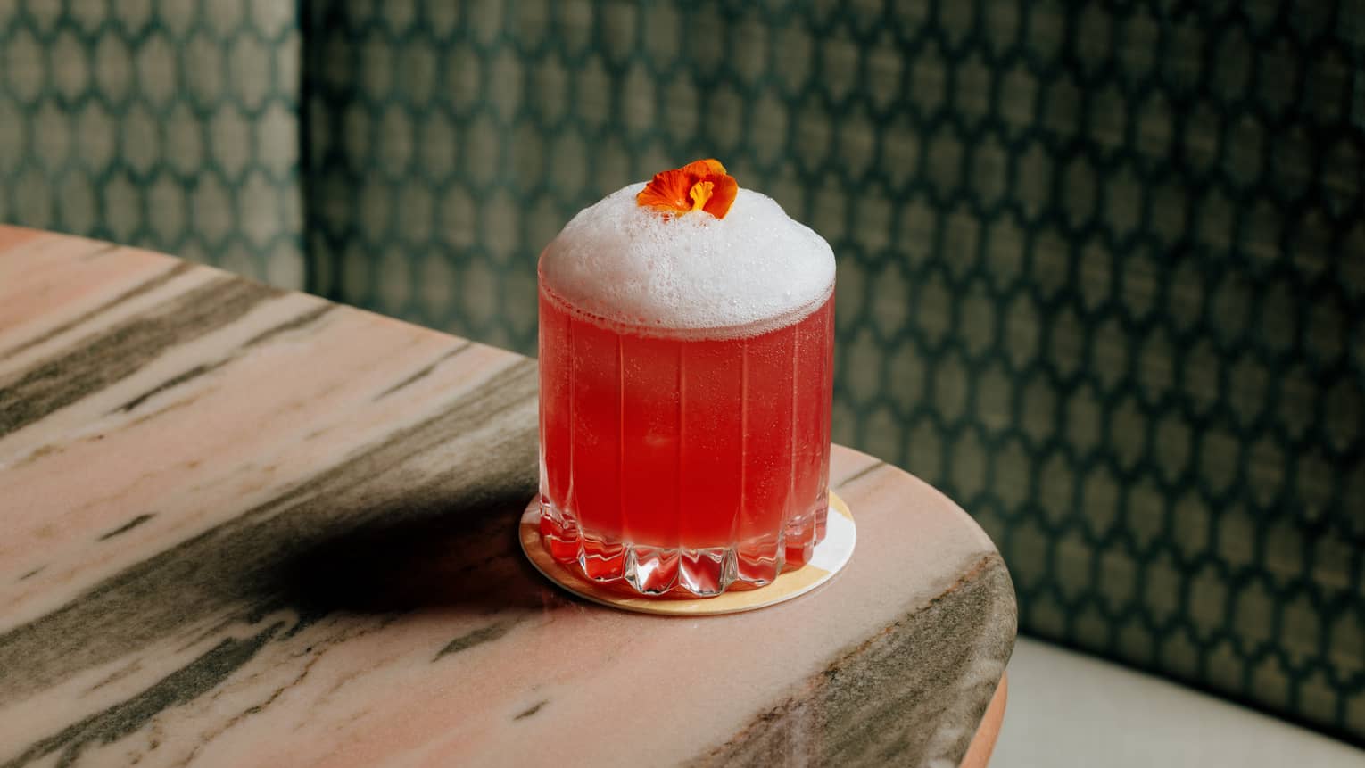 Pomegranate cocktail served in a rocks glass and topped with foam