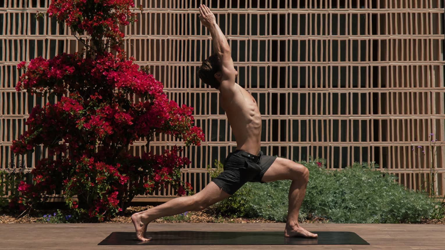 A person in a yoga pose on a mat in an outdoor courtyard