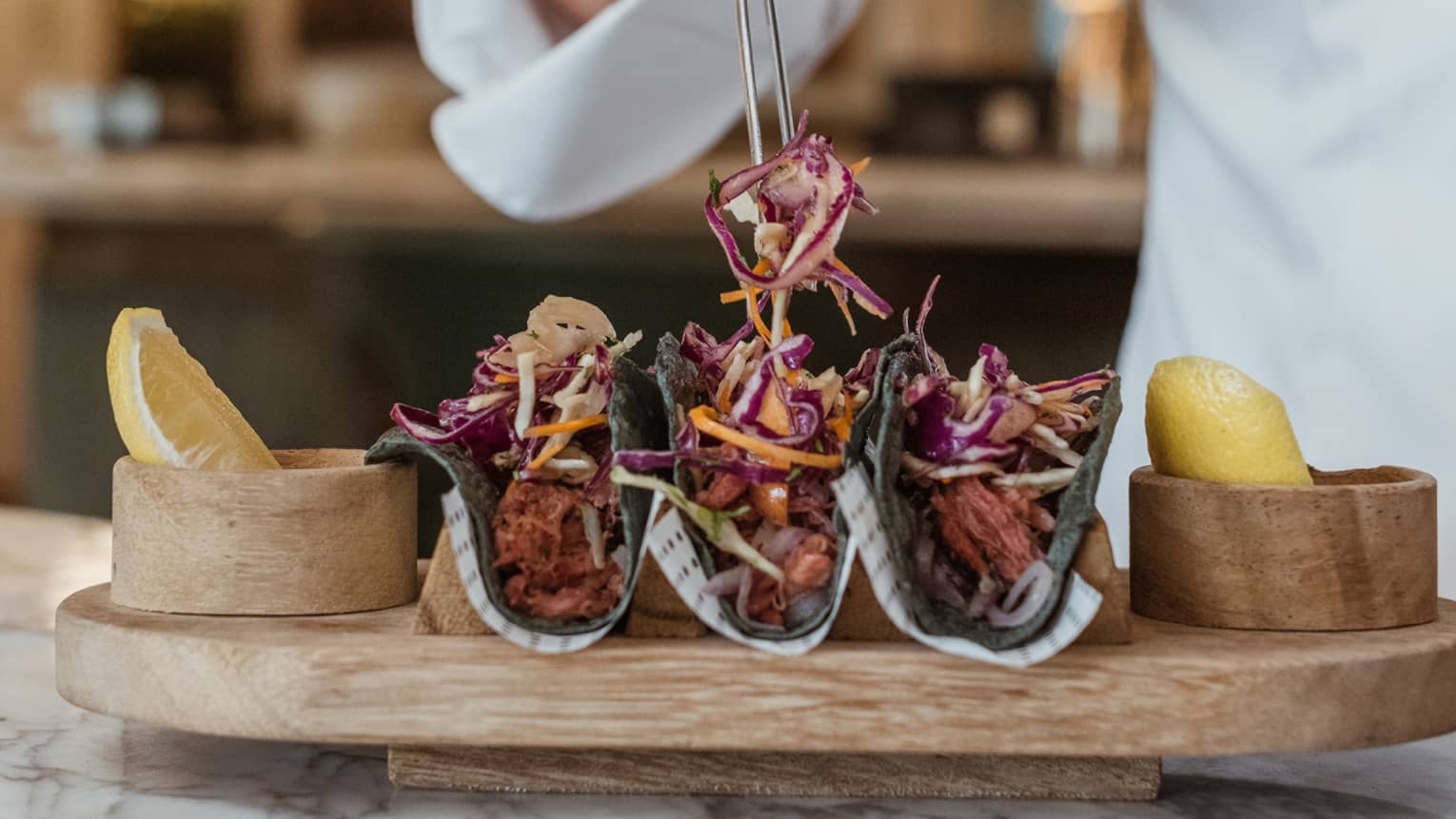 Chef arranging tacos on wooden platter