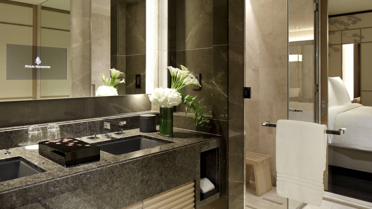 Luxury hotel bathroom with double sinks, marble countertops and fresh white flowers