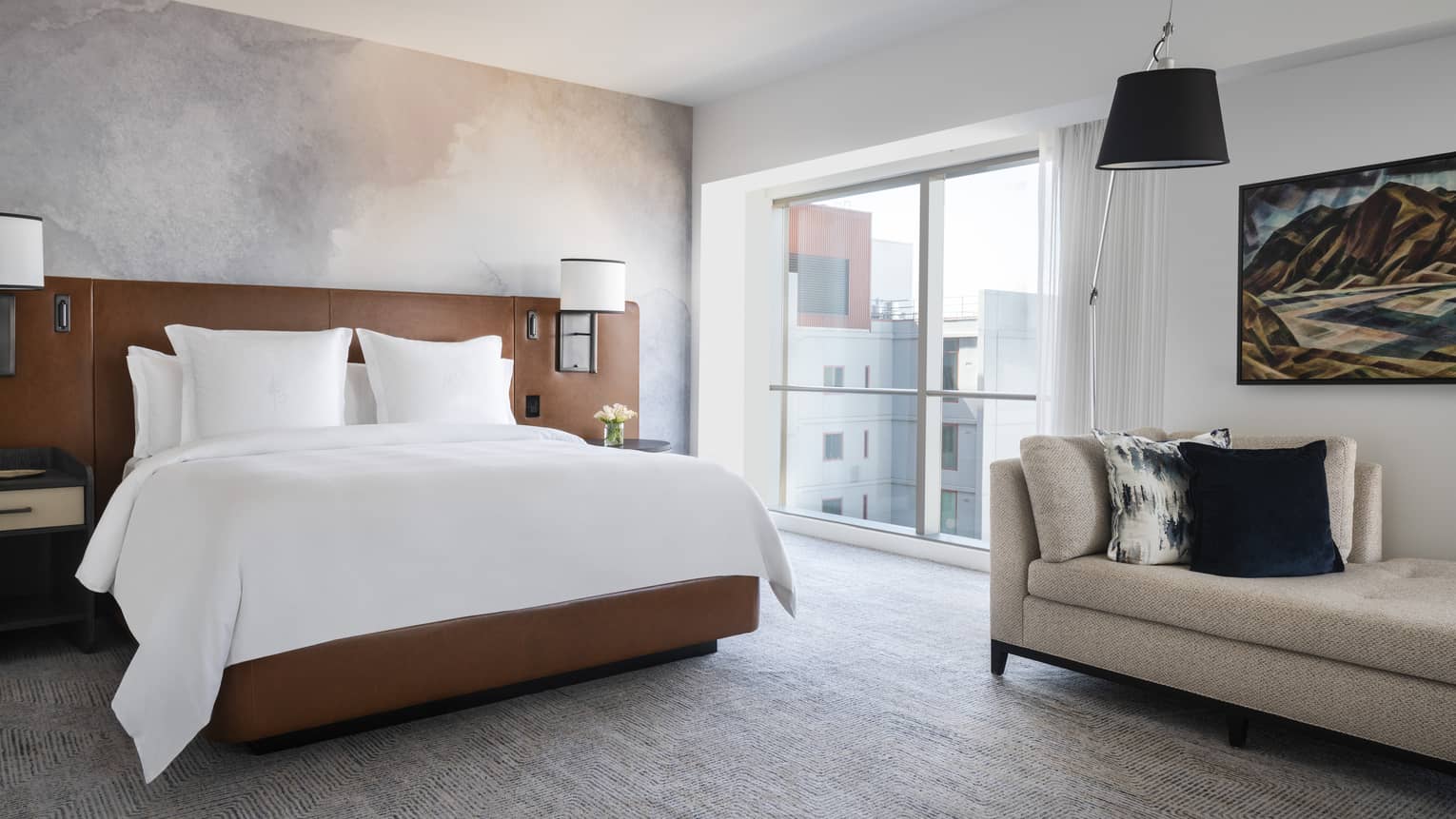 Light streams onto a bed and couch in the Prime Bay View Room