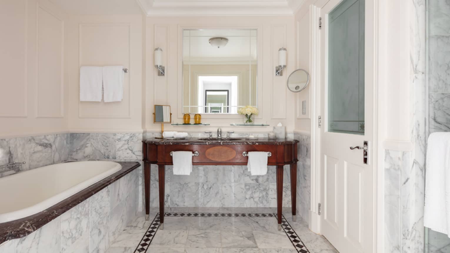 Bathroom with marble accents, large soaking tub, double wooden vanity, mirror