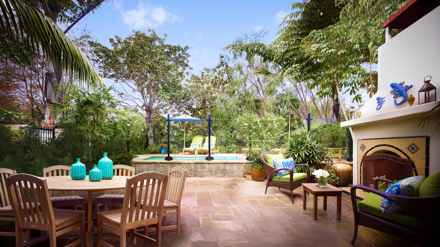 Ortega Bungalow patio with palm tree over wood dining table, outdoor fireplace with colourful Spanish tiles
