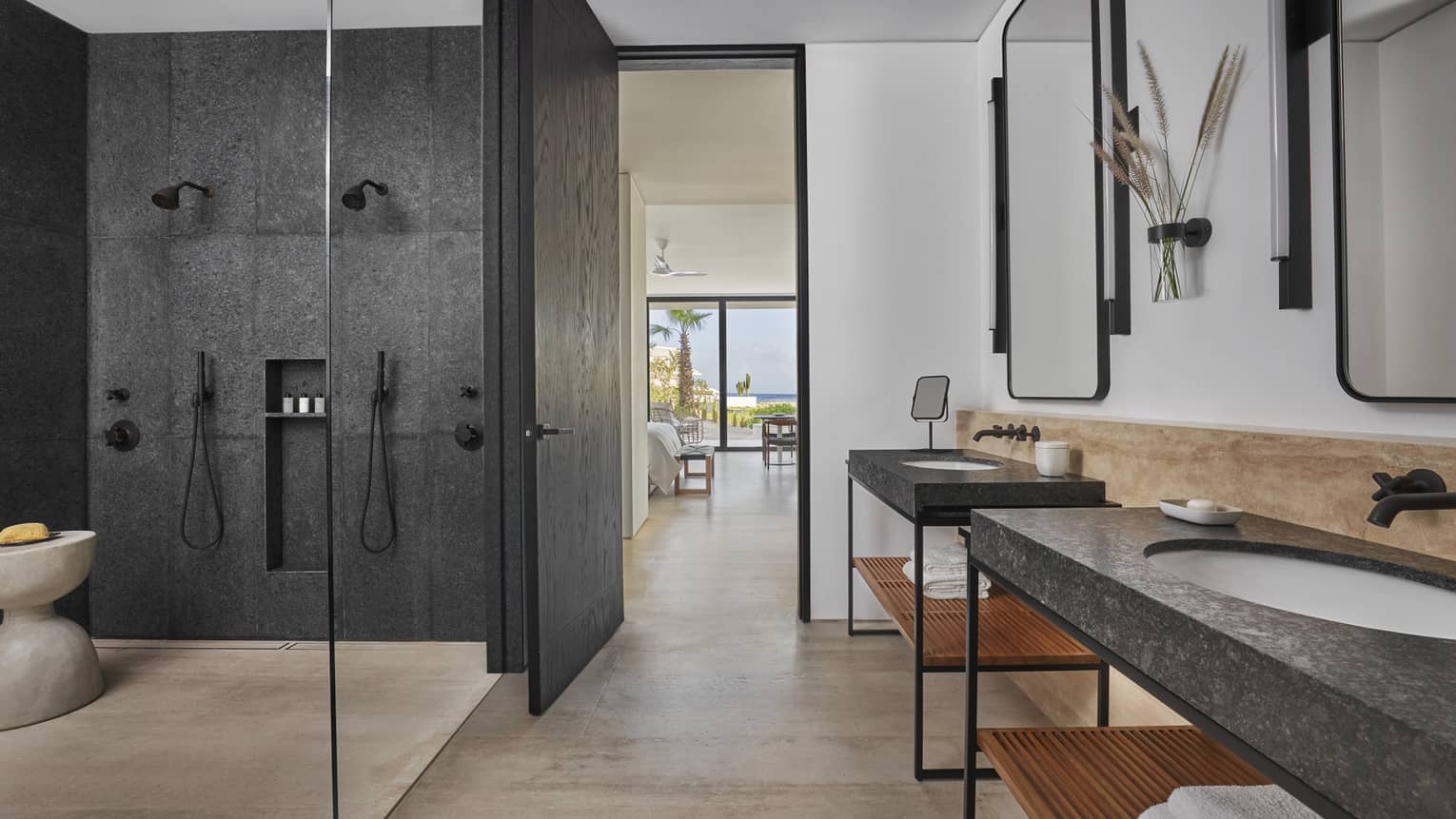 Large modern bathroom with two separate vanities, black stone shower