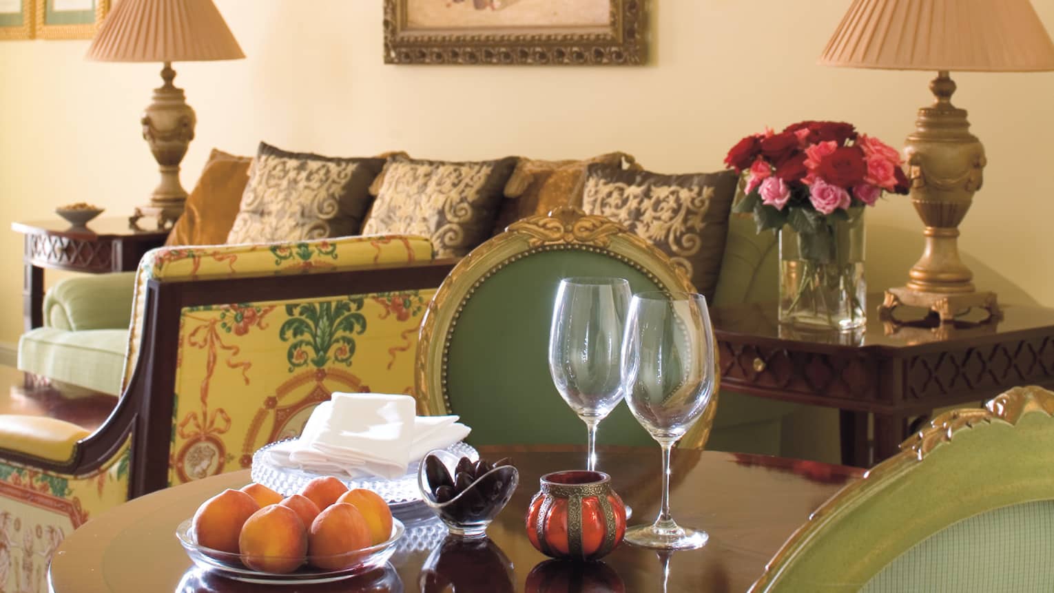 Close-up of wood dining table, wine glasses, bowl with oranges in Four Seasons Executive Suite