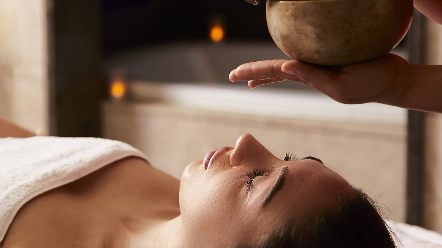 A woman receiving a spa treatment with bowls to create sounds.
