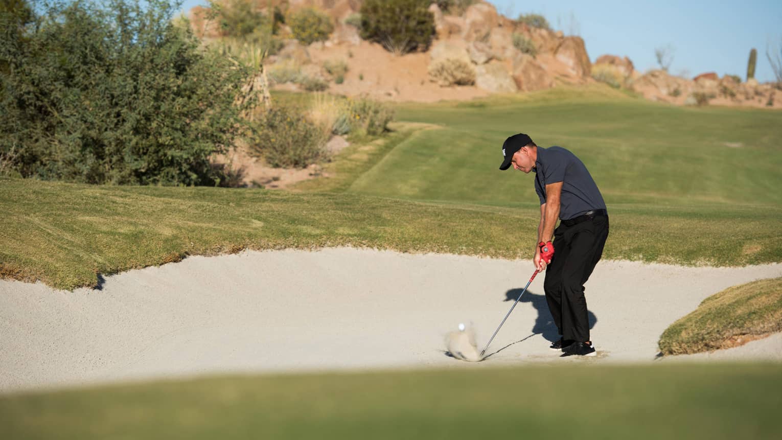 Gabriel Hjerstedt hits a golf ball out of a sand trap
