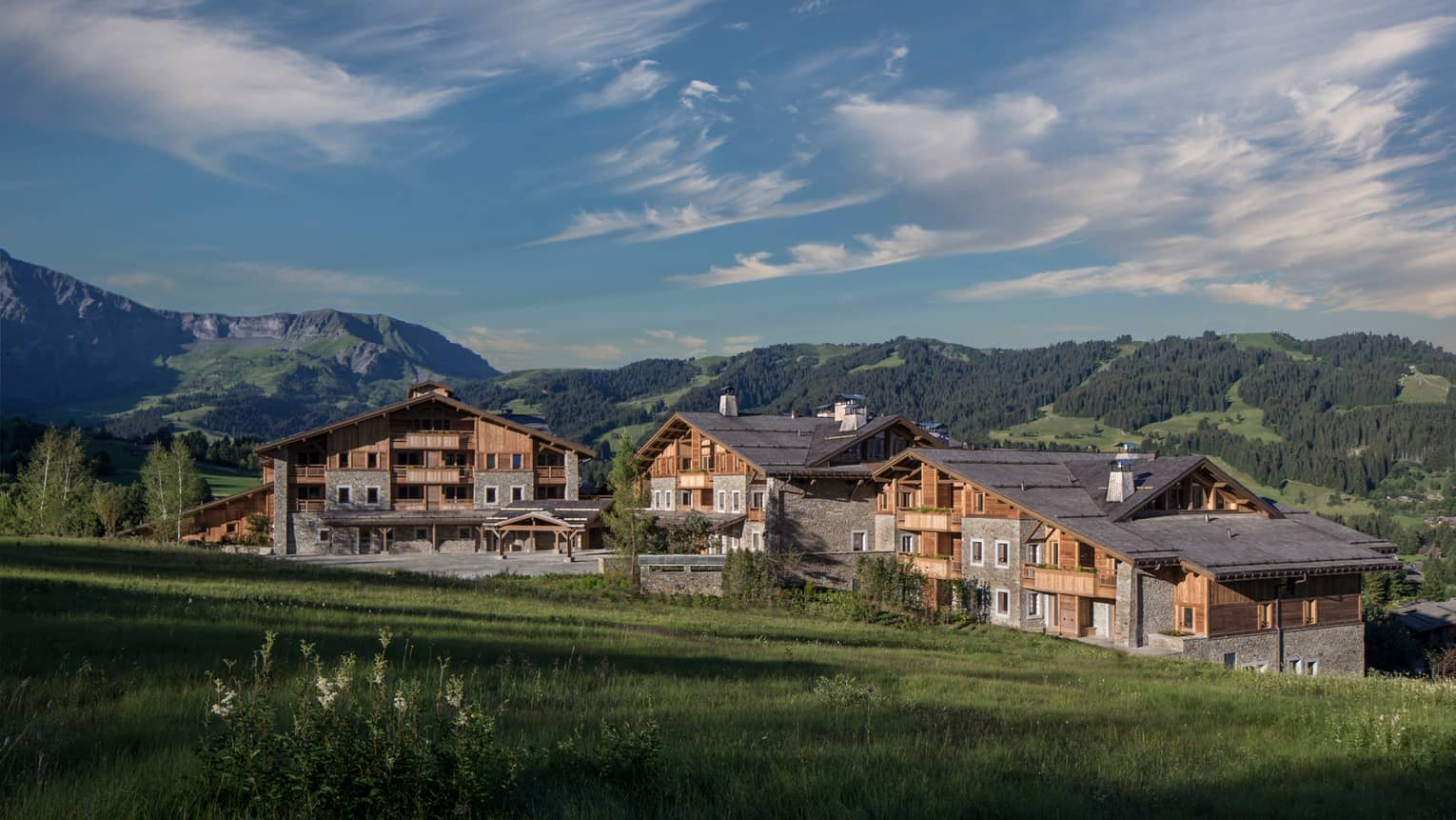 Four Seasons Hotel Mègeve rustic ski resort at edge of meadow, mountains