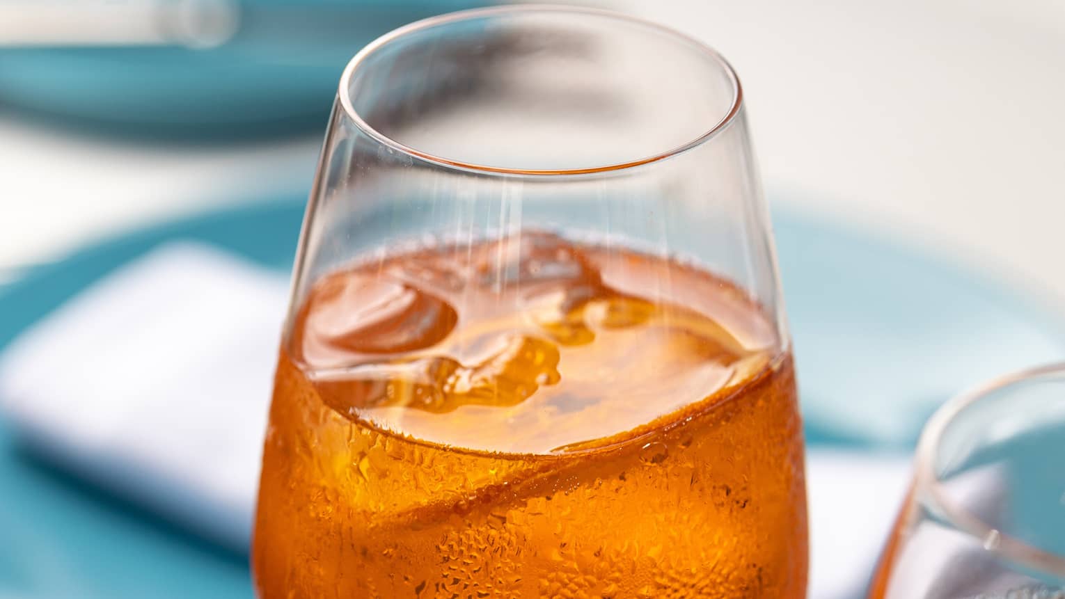 Two amber-coloured iced beverages in tall wine glasses