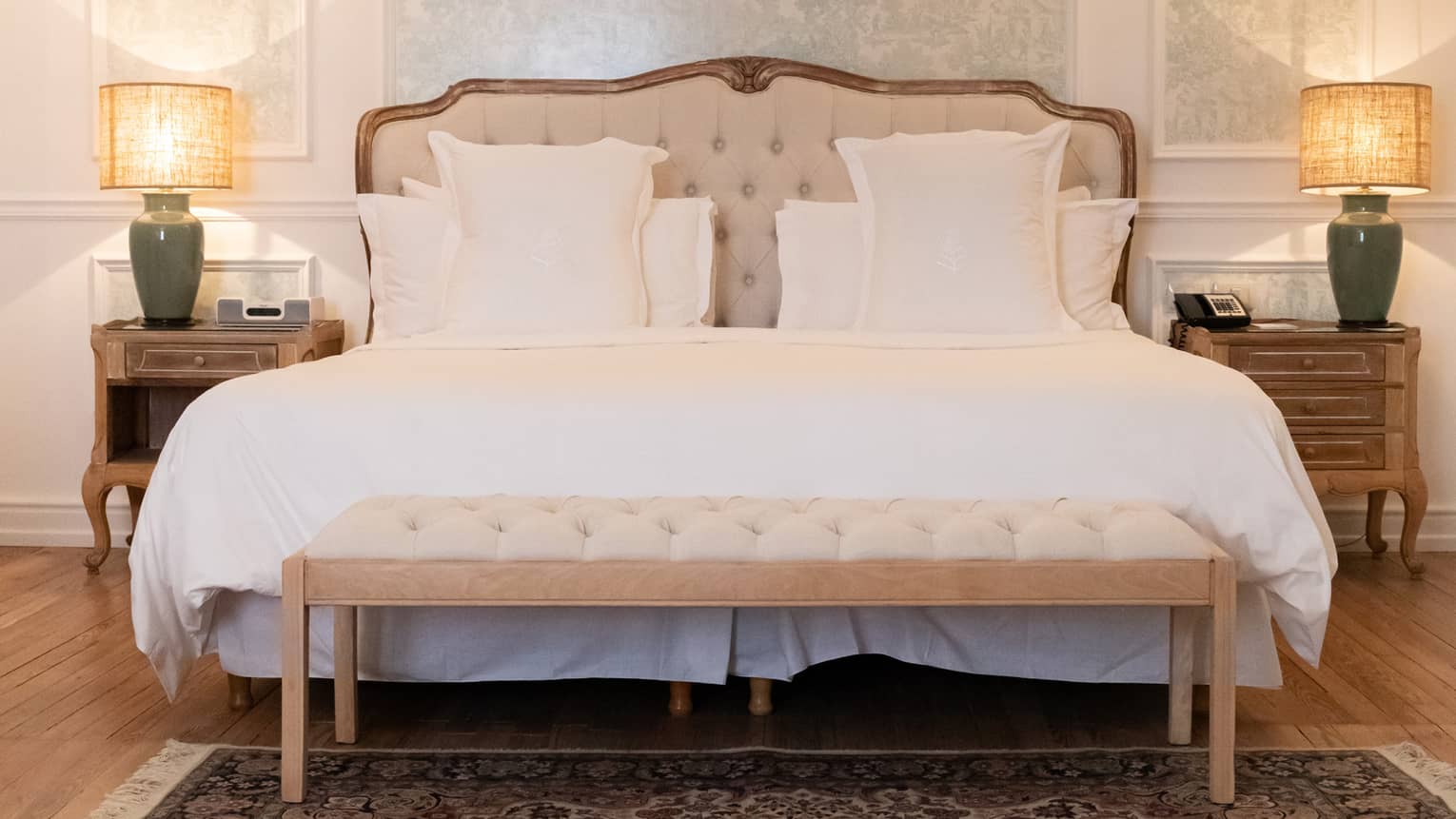 White king bed with upholstered headboard, two hanging sconces, light blue accent wall