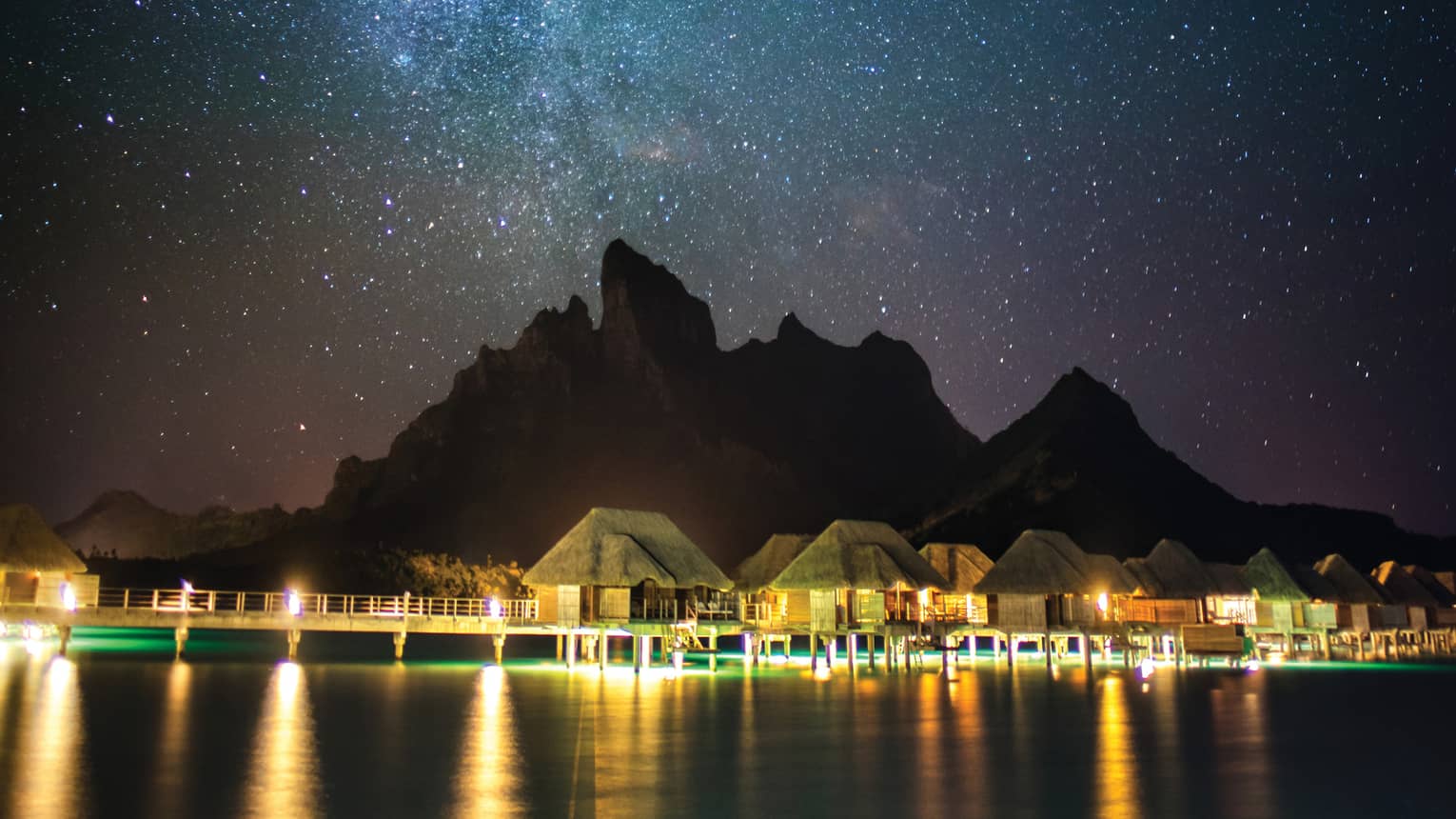 Illuminated Four Seasons Resort Bora Bora beneath a blanket of stars at night