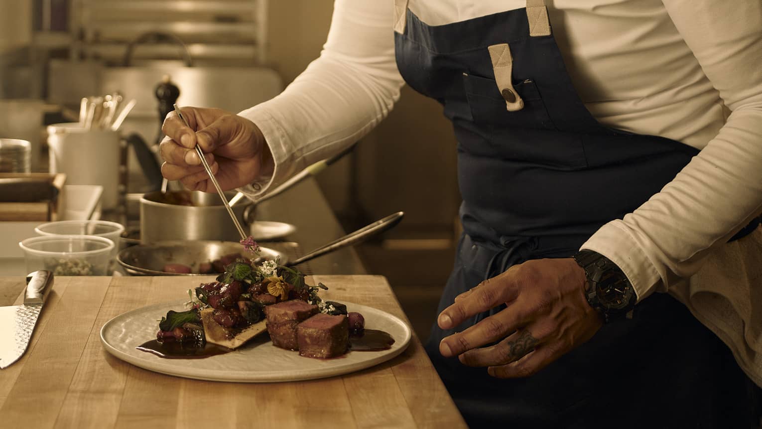 Chef places garnish onto a steak dish