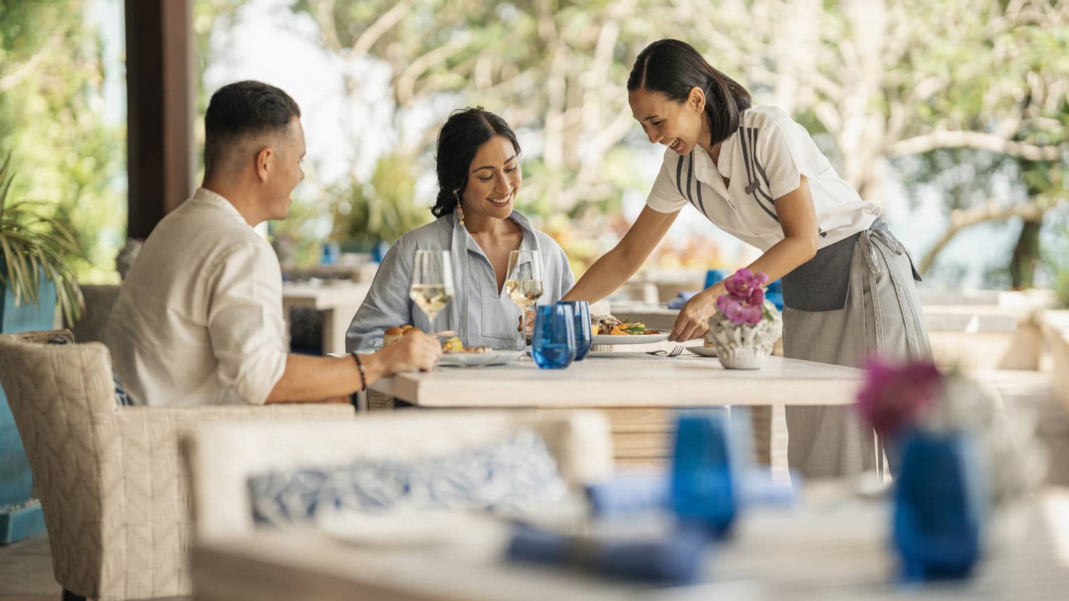Female server brings dish to smiling couple's table at Pla Pla