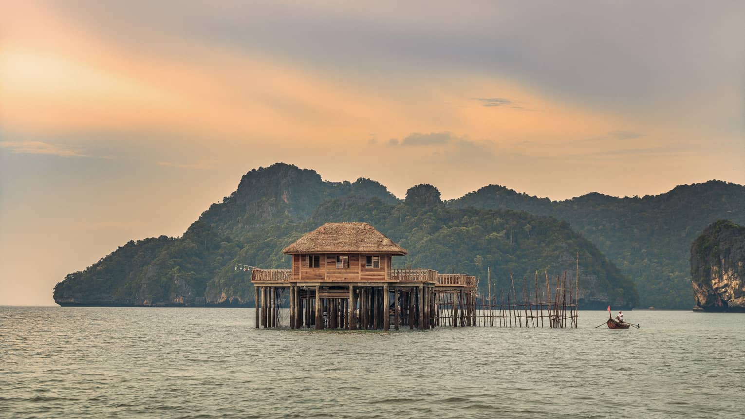 A sunsetting over a lake with huts on it in Langkawi 