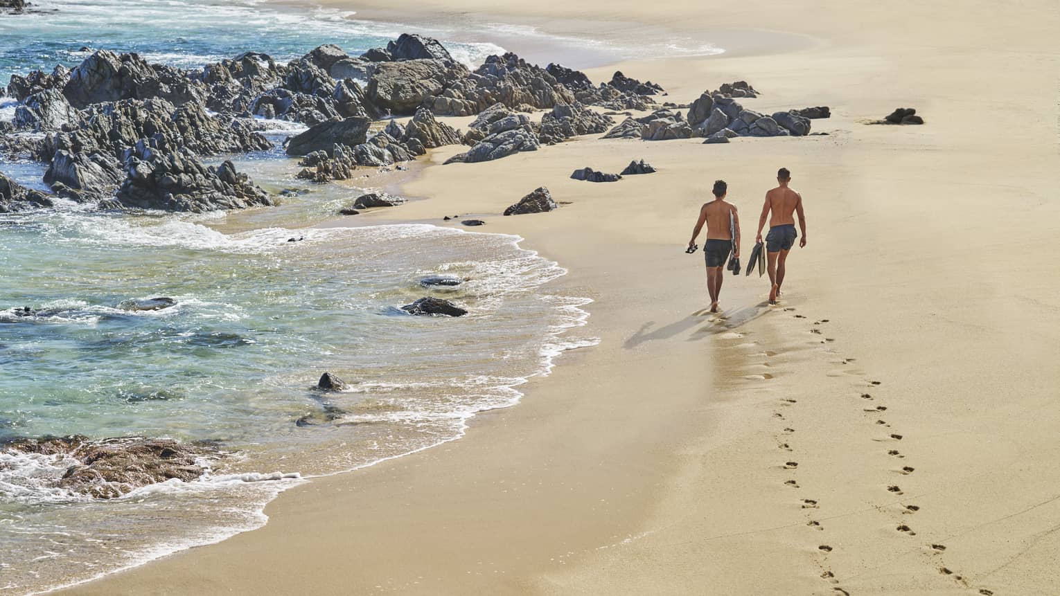 A couple stroll along the beach in Cabo San Lucas