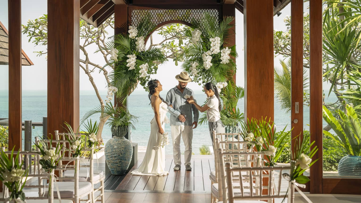 Wedding staff member pins traditional Thai flower boutonniere on groom
