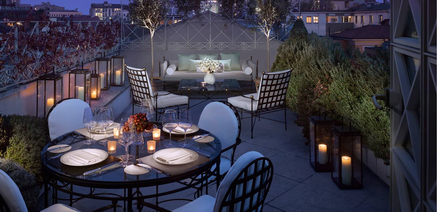 Penthouse Suite lantern-lined rooftop balcony, candle-lit dining table, patio sofa and chairs at night