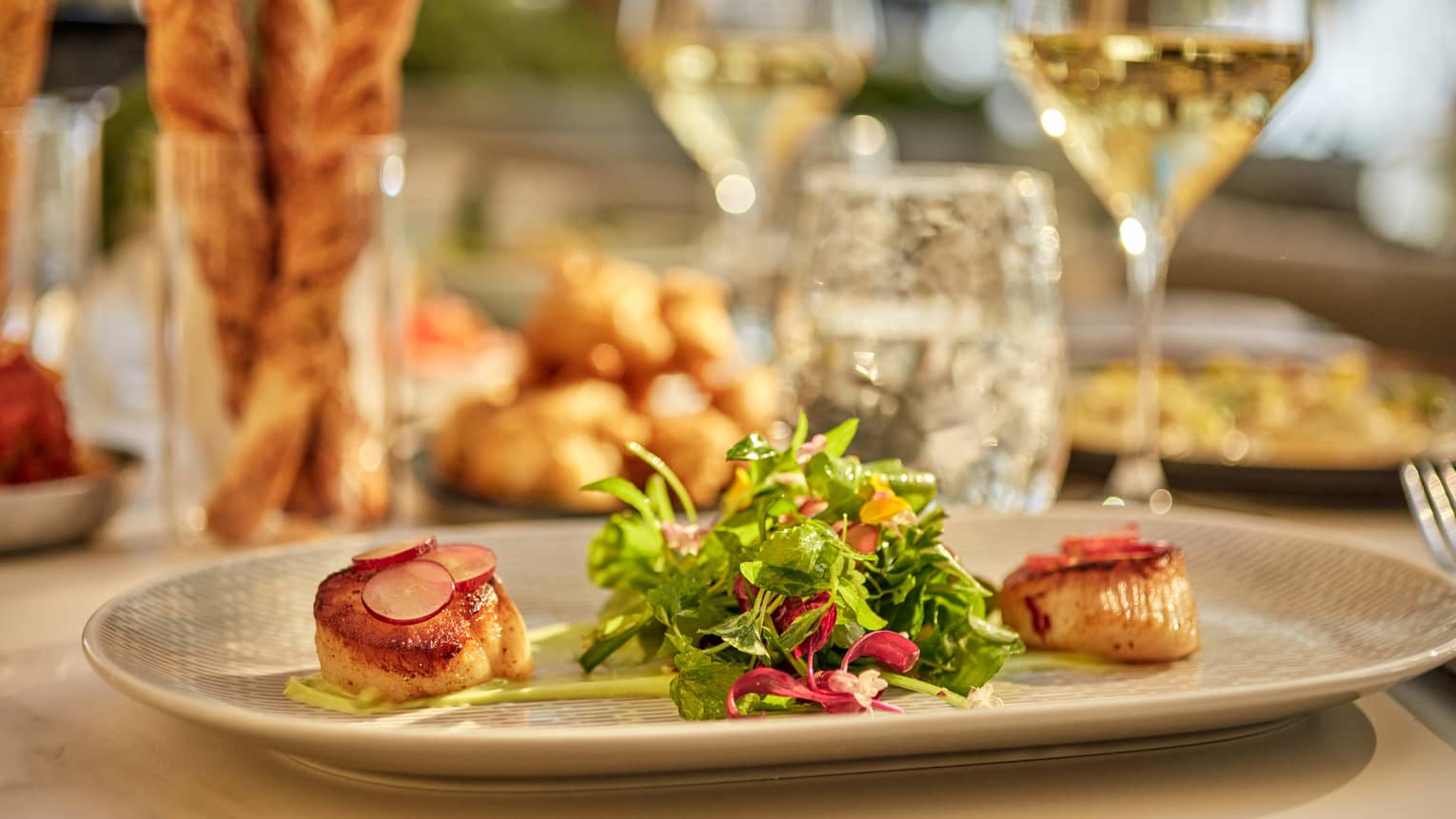 Scallop and greens on a plate.