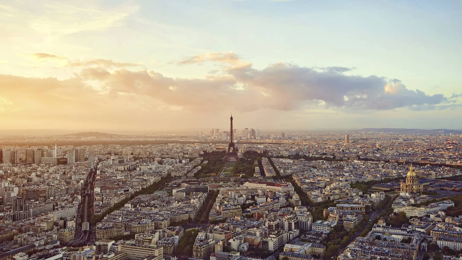 Sweeping city view of Paris rooftops, buildings, Eiffel tower at sunset