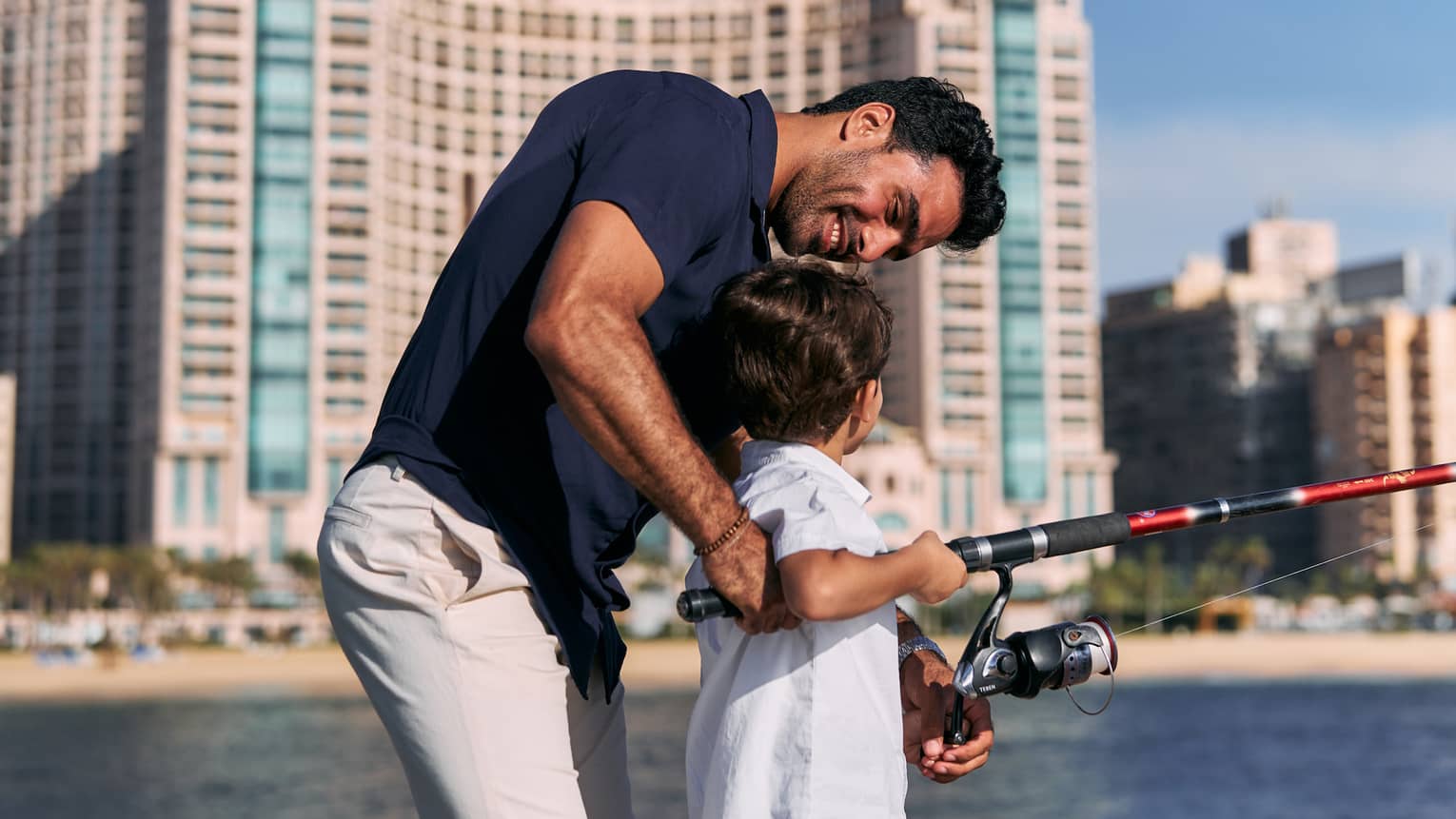 Parent guides young child with a fishing pole