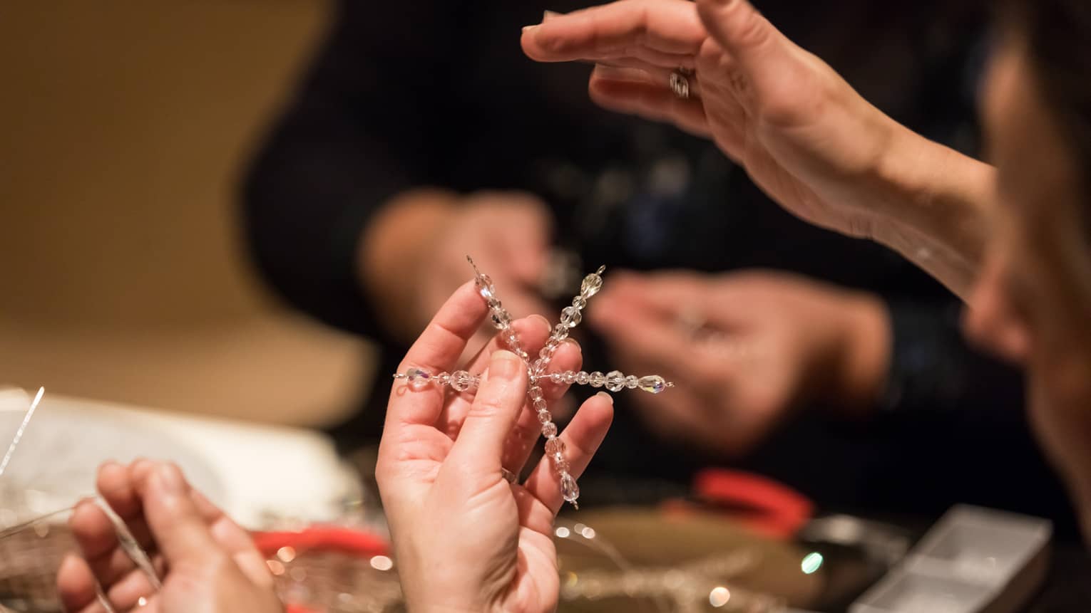 Hands stringing beads on star-shaped craft