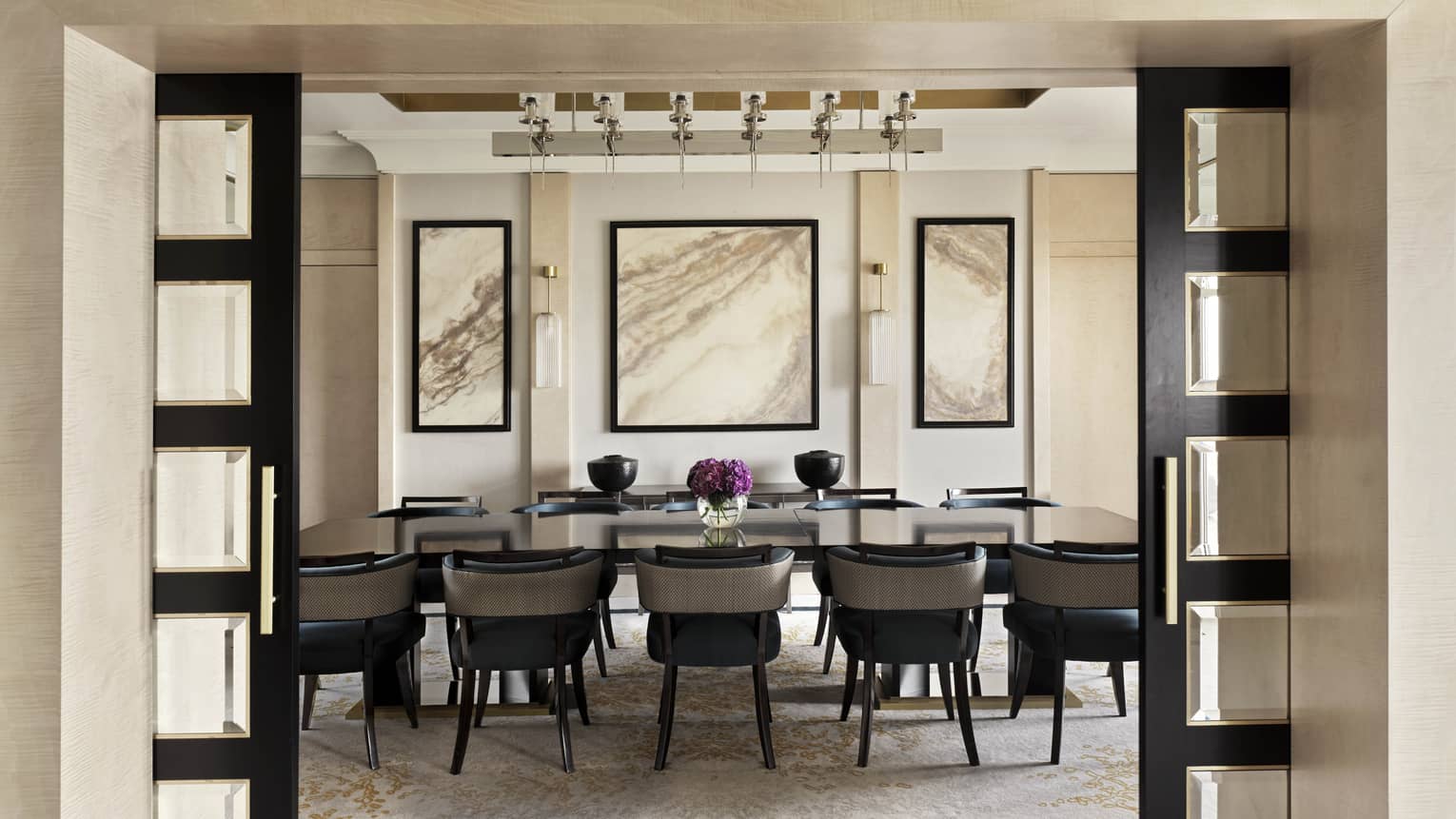 Royal Suite dining room featuring a long dark-wood table set for 10 with three abstract textural paintings on the wall behind the table