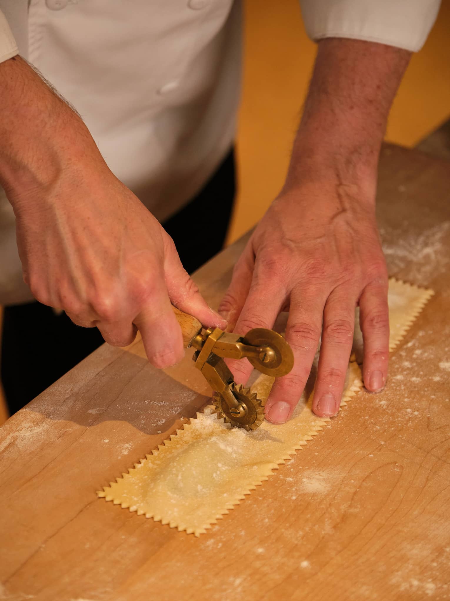 A chef crimping a sheet of ravioli pasta