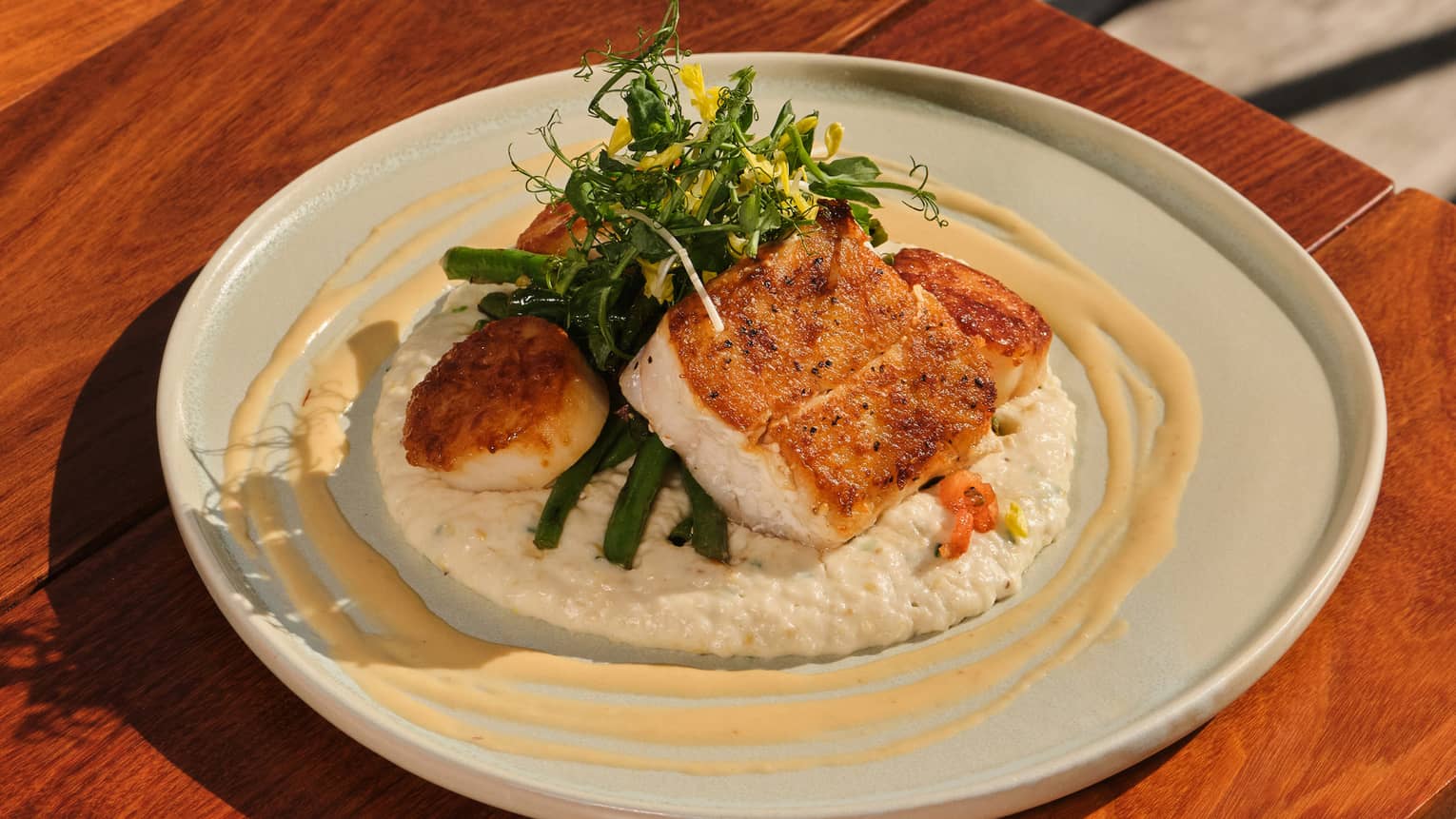 Roasted grouper and scallops served with grits, green beans and saffron lobster jus