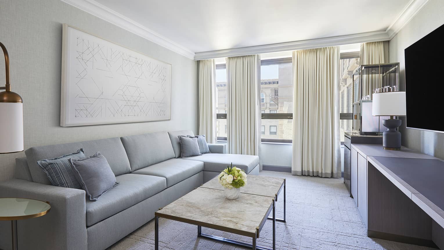 Living room with light blue sofa, coffee table, TV and windows