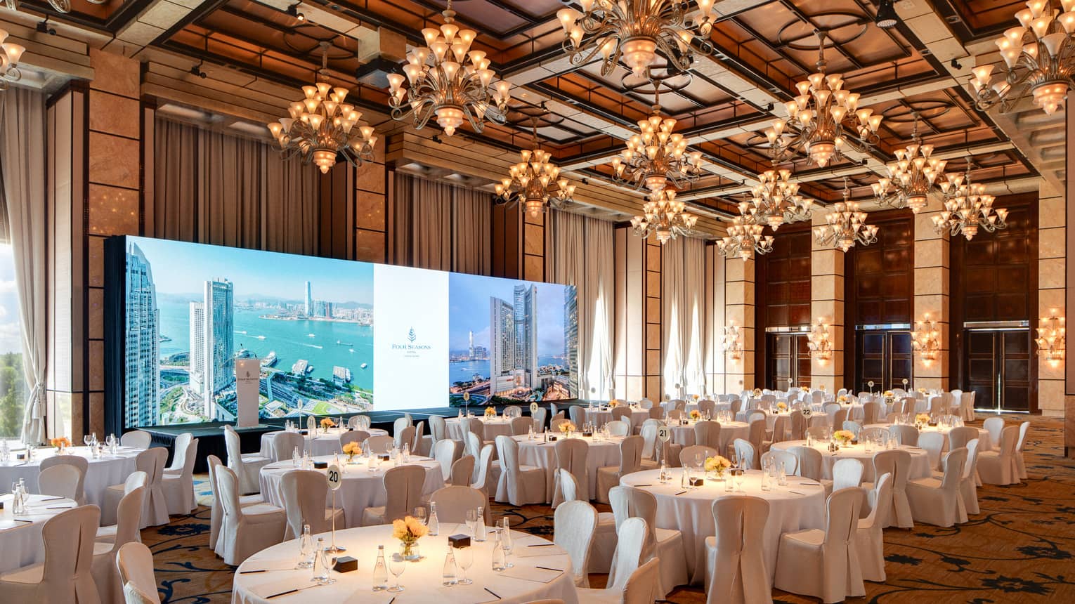 Large hotel ballroom with banquet seating an wide screen in the front of the room