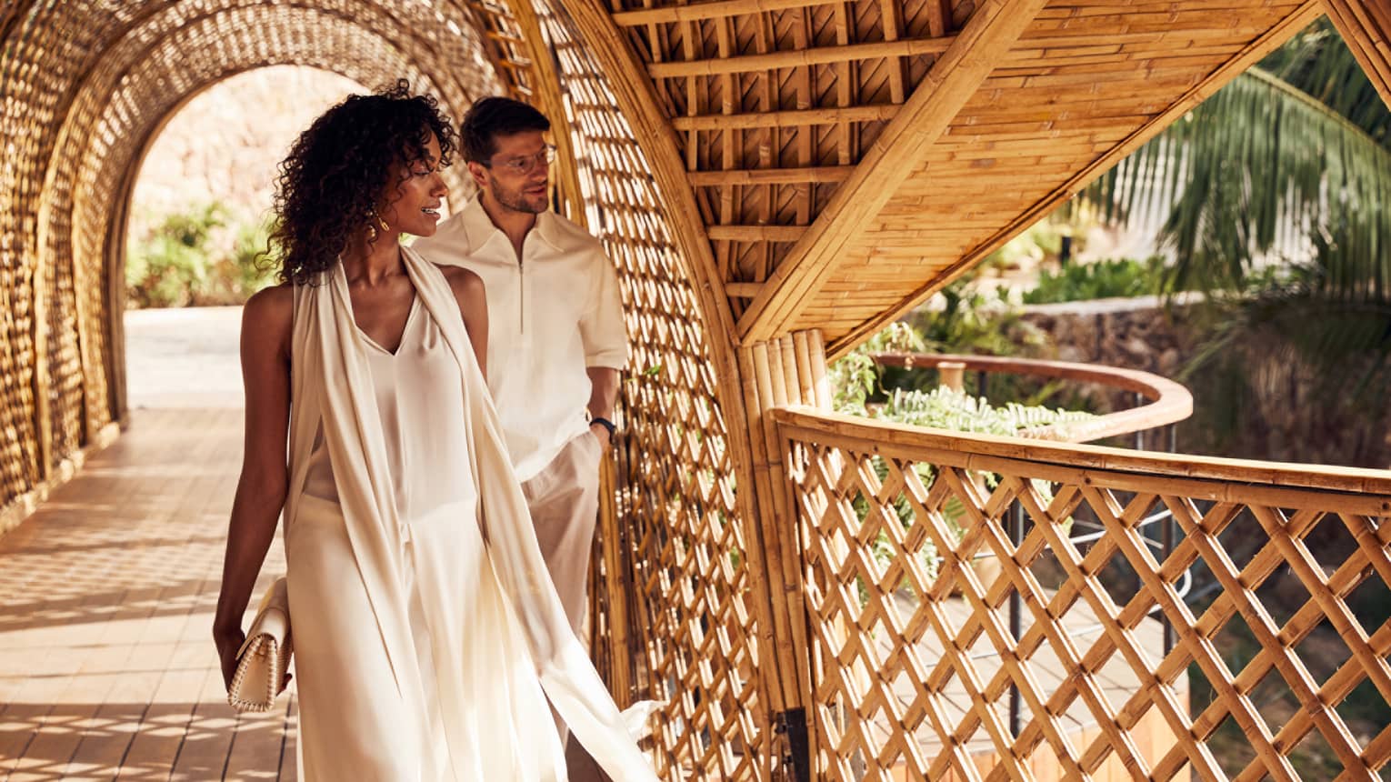 A woman and man walking through a covered path outside.