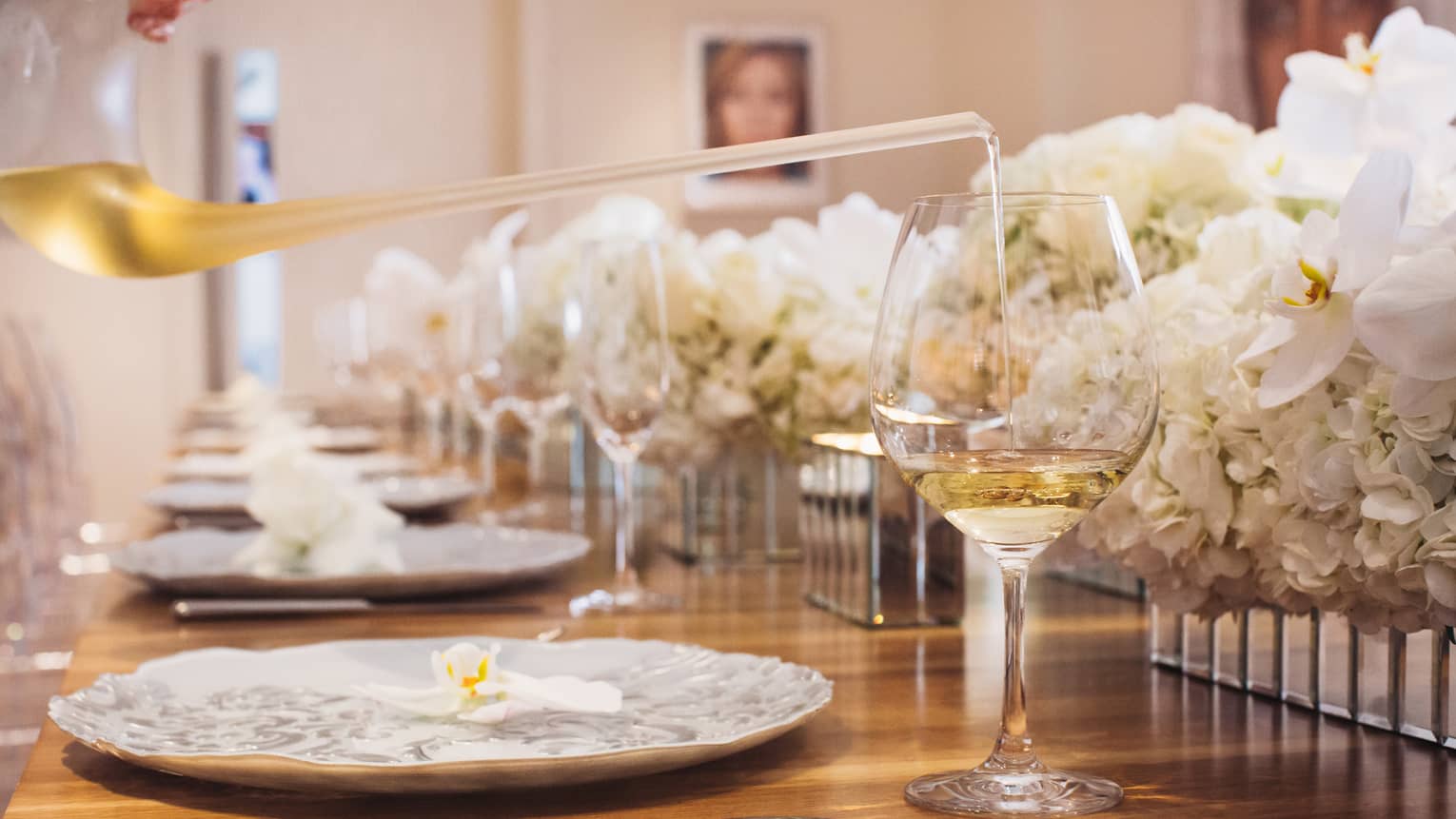 Close-up of glass of white wine, white roses along formal banquet table