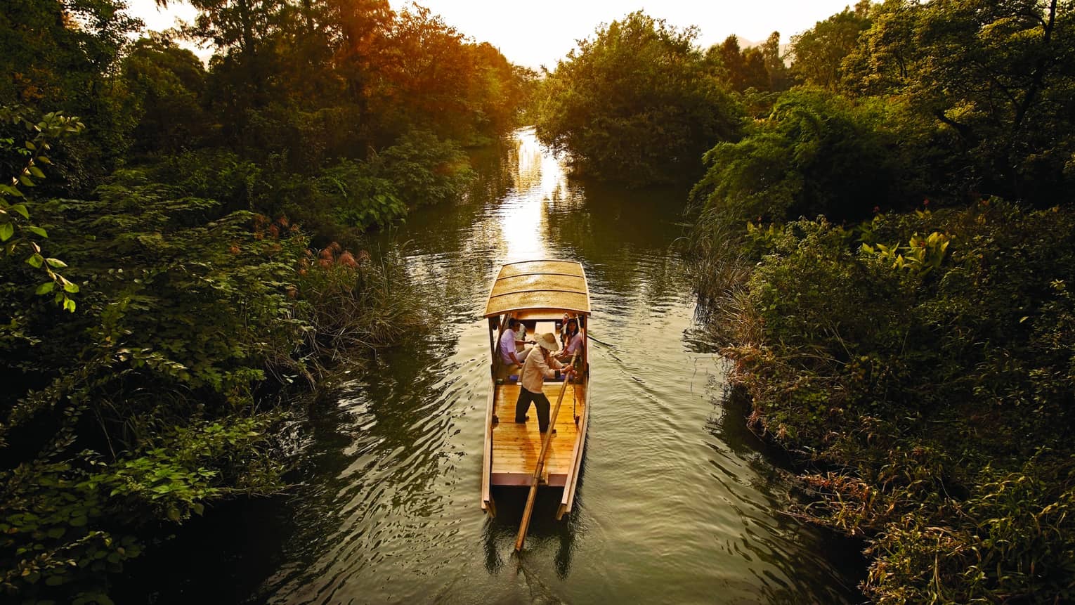 Traditional Chinese wooden boat sails down river in Xixi Wetland National Park