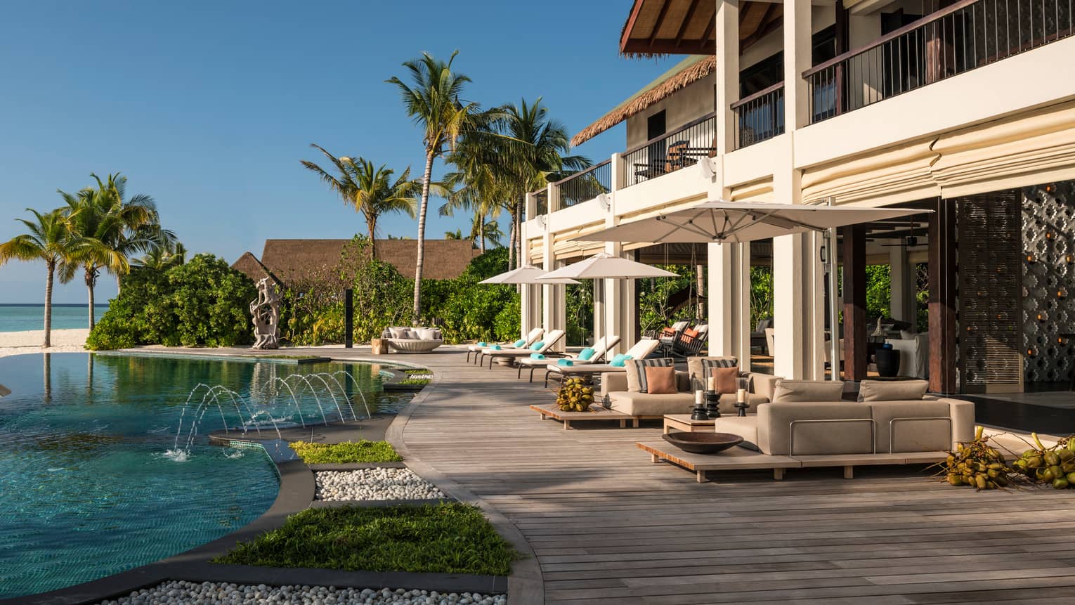 Swimming pool, wood patio under two-storey villa, palm trees