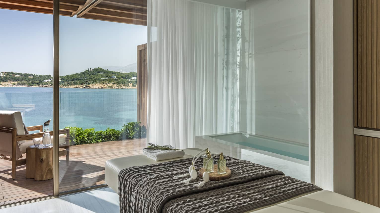 White spa table with dark blanket and water view from tall windows