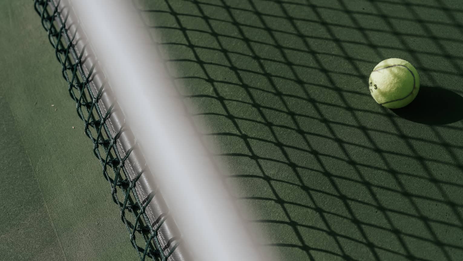 Tennis ball on tennis court with shadow of net