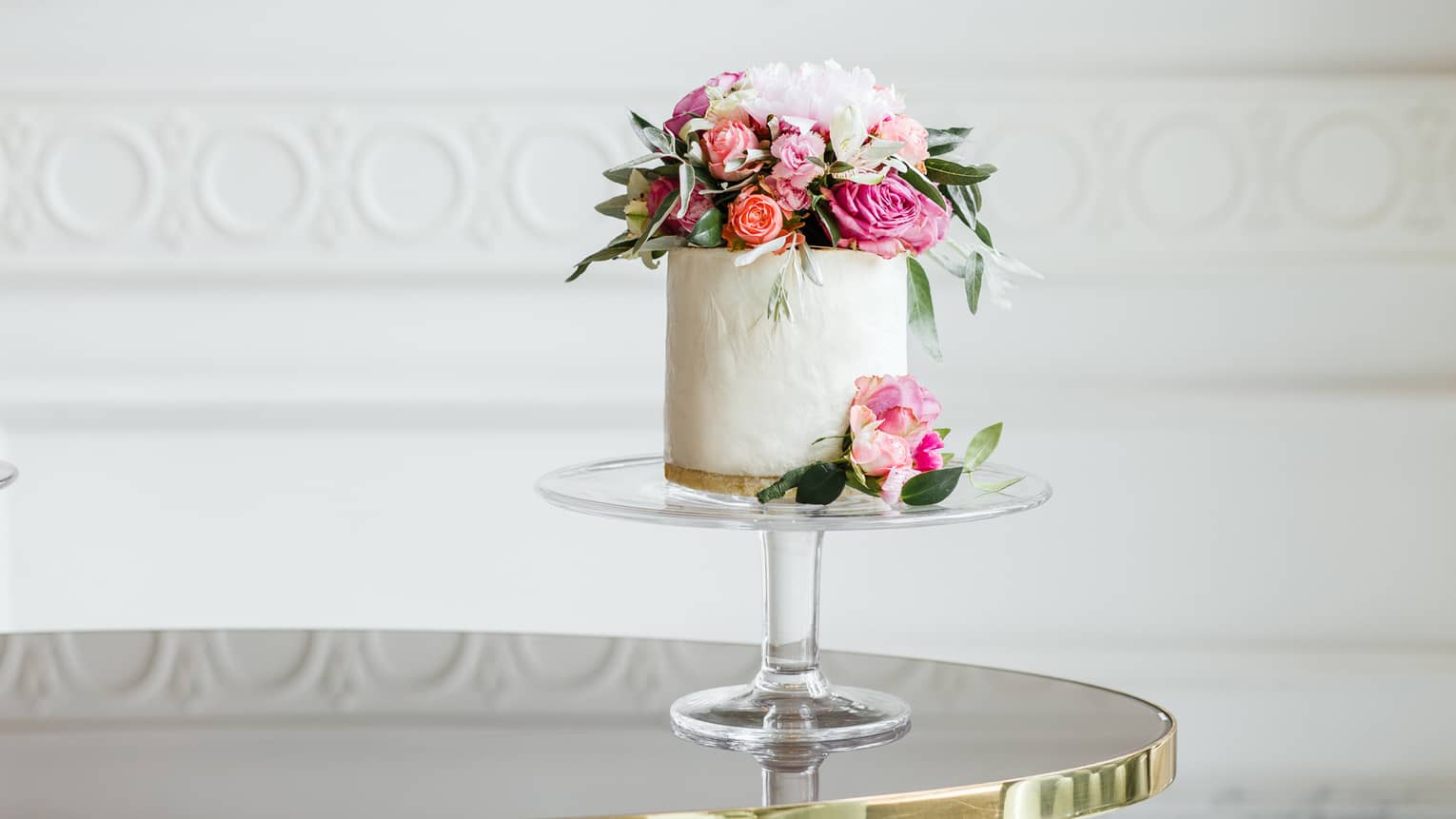 Elegant small white wedding cake topped with fresh pink and white roses 