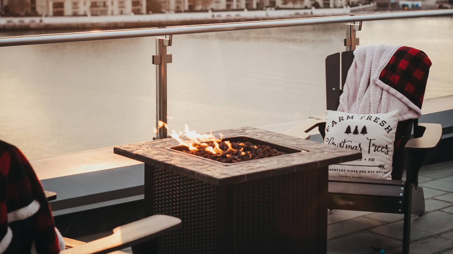 Two chairs seated around a fire pit overlooking the river.