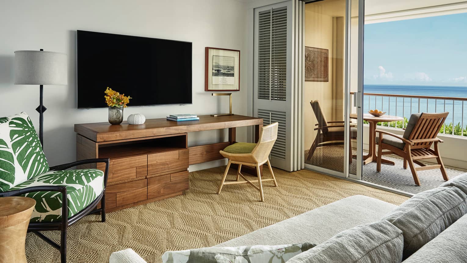 Oceanfront Suite large rustic wood desk under TV, palm print chair, open balcony doors