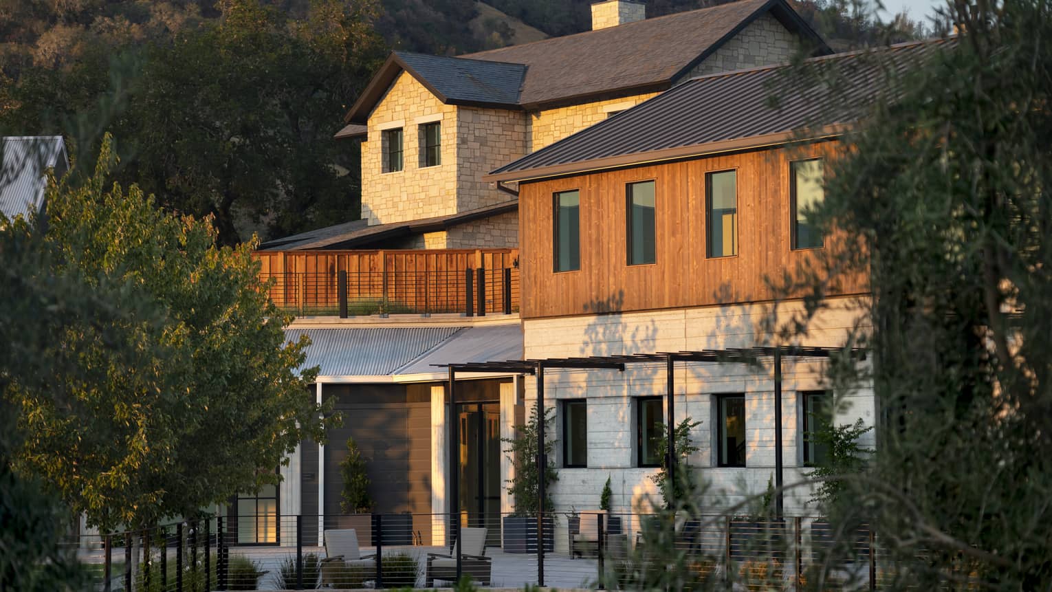 An exterior of a large building surrounded by trees and a large hill or mountain.