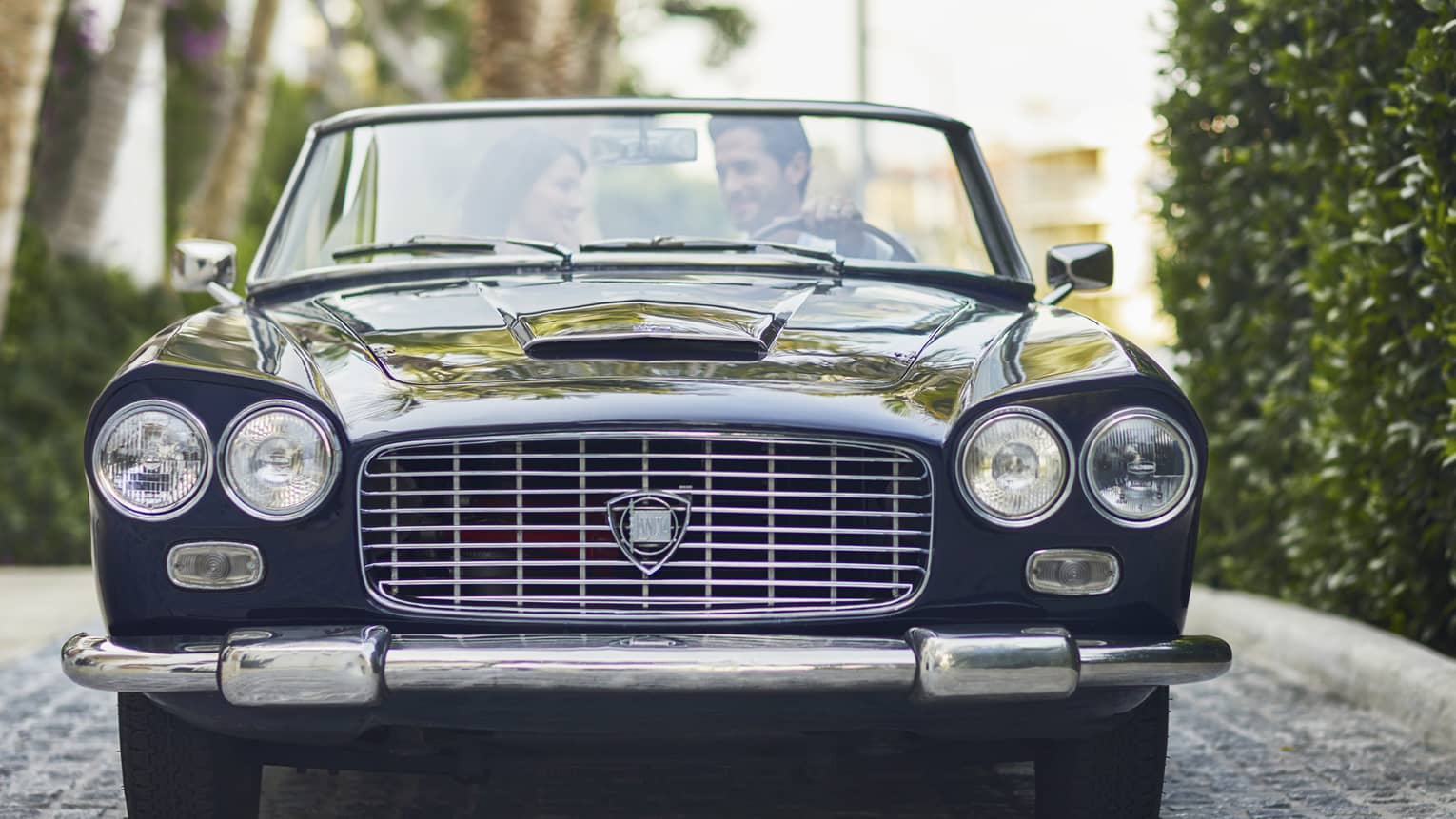 Man and woman sit in black vintage car smiling 