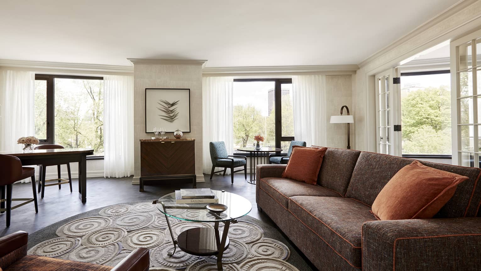 Bright State Suite living room with long rustic red sofa, small glass table, swirl rug, retro-style bar and dining cafe table