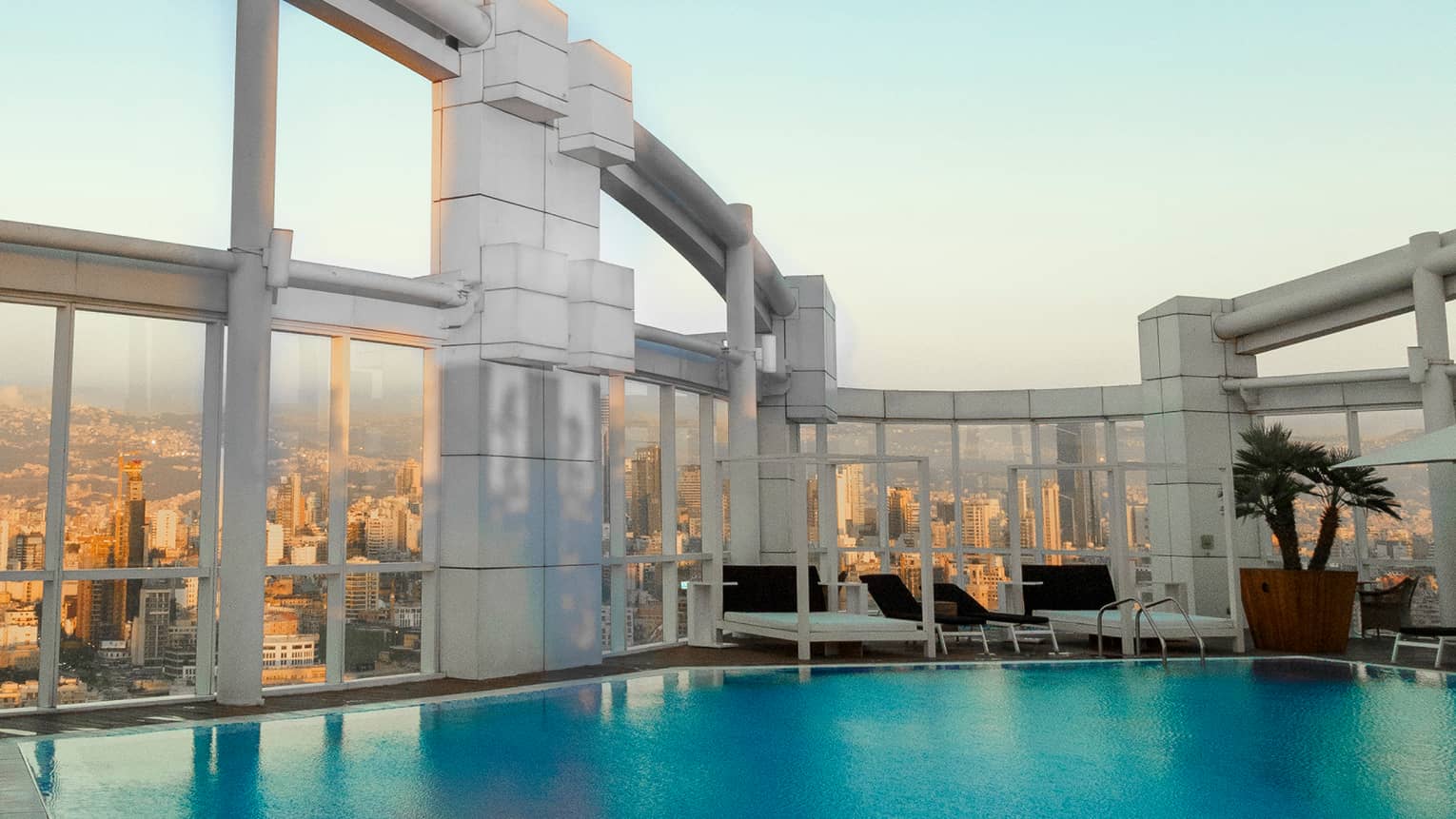 Outdoor pool looking up at pool chairs and pillars, 26th floor view of city from deck