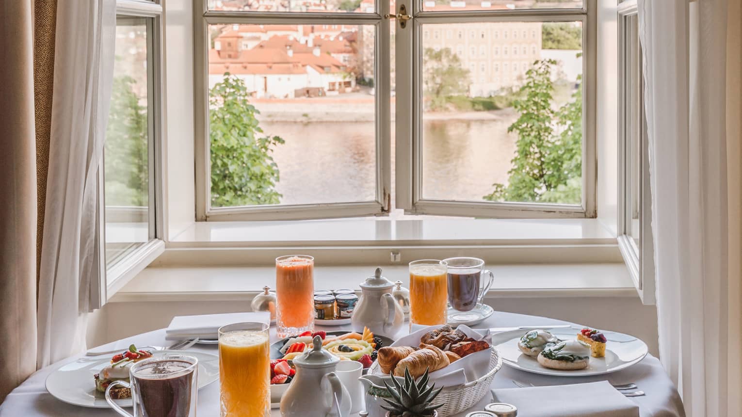 Alcove with round clothed table set for in-room breakfast with views of the Vltava River