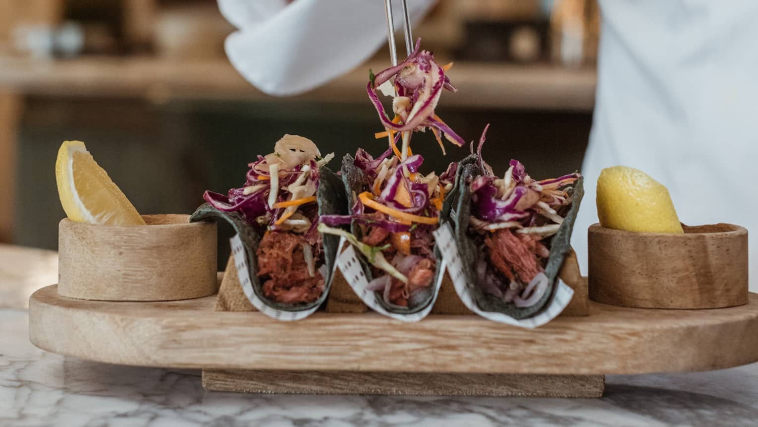 Chef arranging tacos on wooden platter