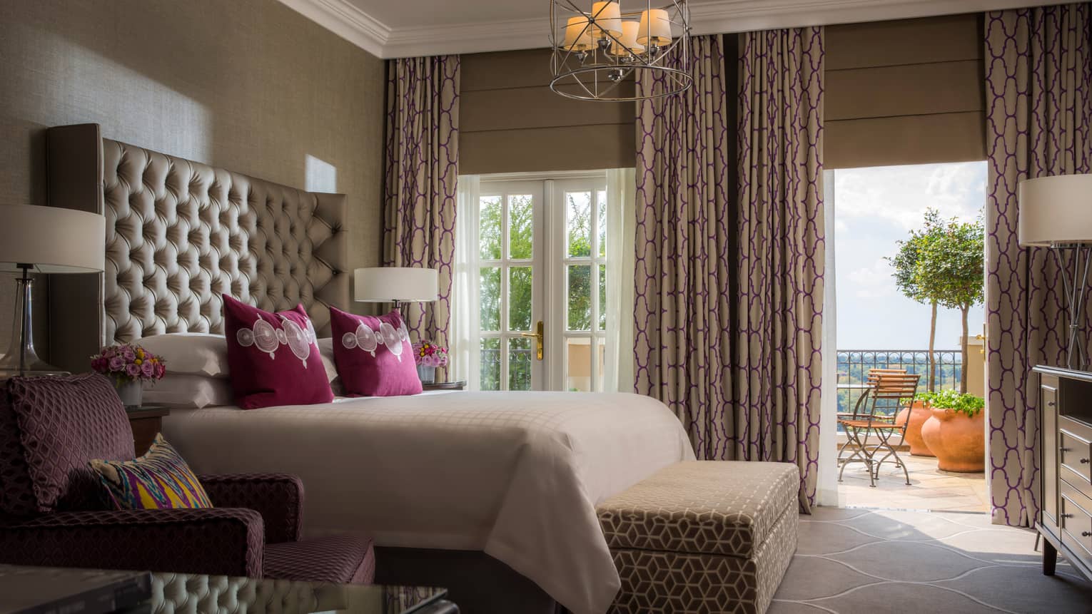 Presidential Suite bed against tall padded headboard, armchair and padded bench, large picture windows with patterned curtains