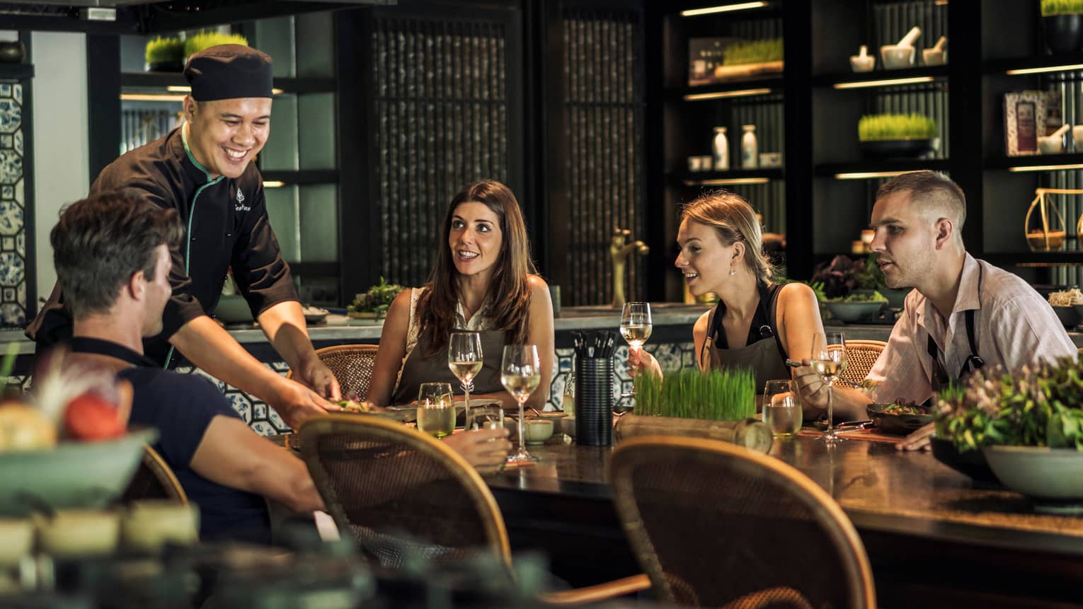 Smiling chef serves table of friends in La Sen dining room
